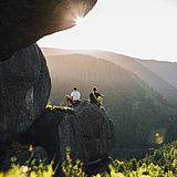 Zwei Personen sitzen auf einem großen Felsen