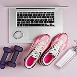 Schuhe, Hanteln, Uhr, Wasserflasche neben einem Laptop