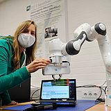 A Person arbeitet mit einem Roboterarm 
