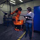 Eine Person bedient einen Roboterarm 