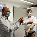 Ein Arzt hält den Impfstoff neben der Person, die geimpft wird