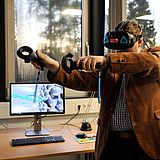 Eine Person trägt ein VR-Headset und hält VR-Controller